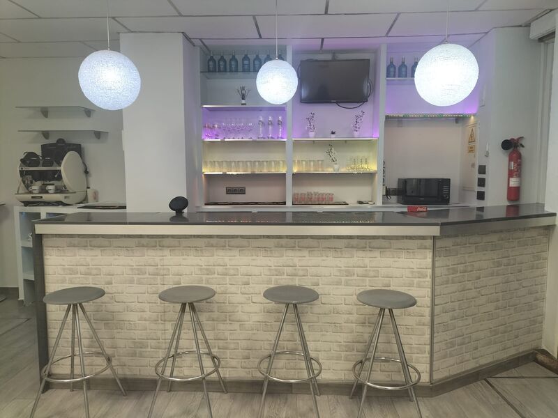 Barra de bar con taburetes y estantería retroiluminada